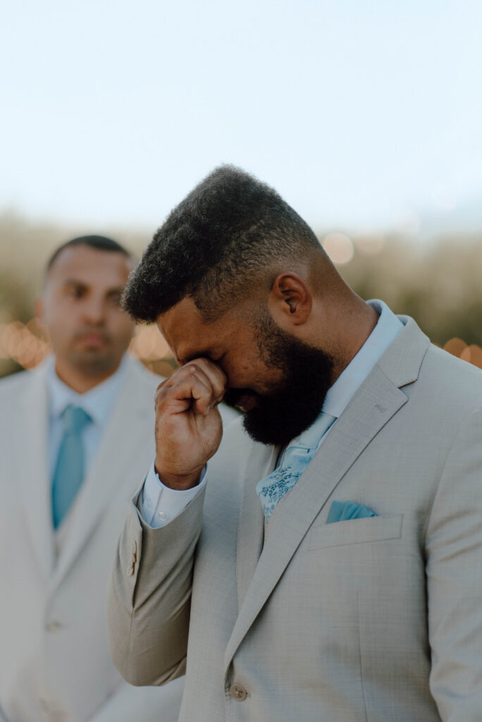 Emotional groom wiping away tears during the outdoor Gansberg Rnach wedding ceremony.