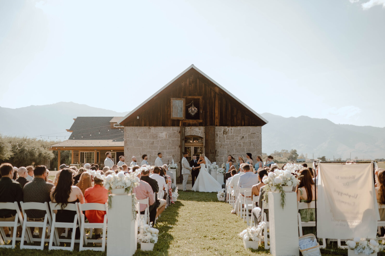 Wide view of an outdoor Gansberg Ranch wedding ceremony in front of the Stone Barn.