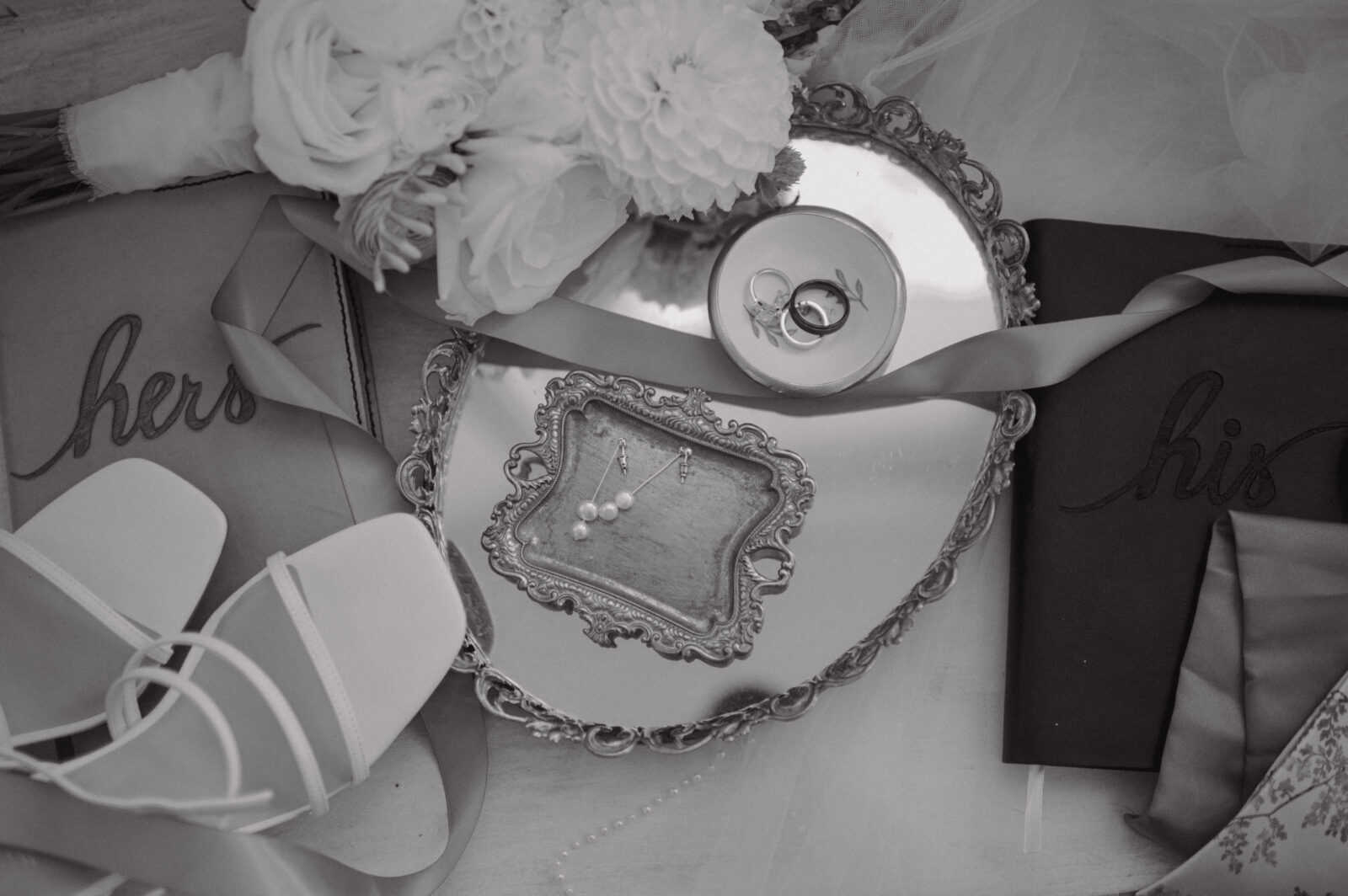 Wedding rings, pearl earrings, bouquet, shoes and vow books.