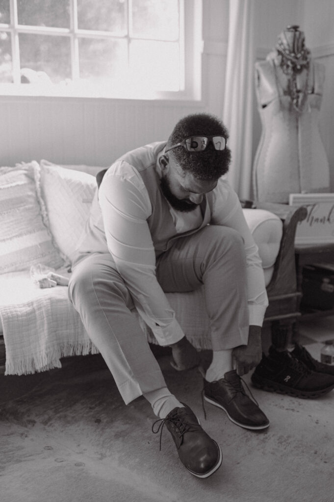 Groom putting on dress shoes while getting ready indoors