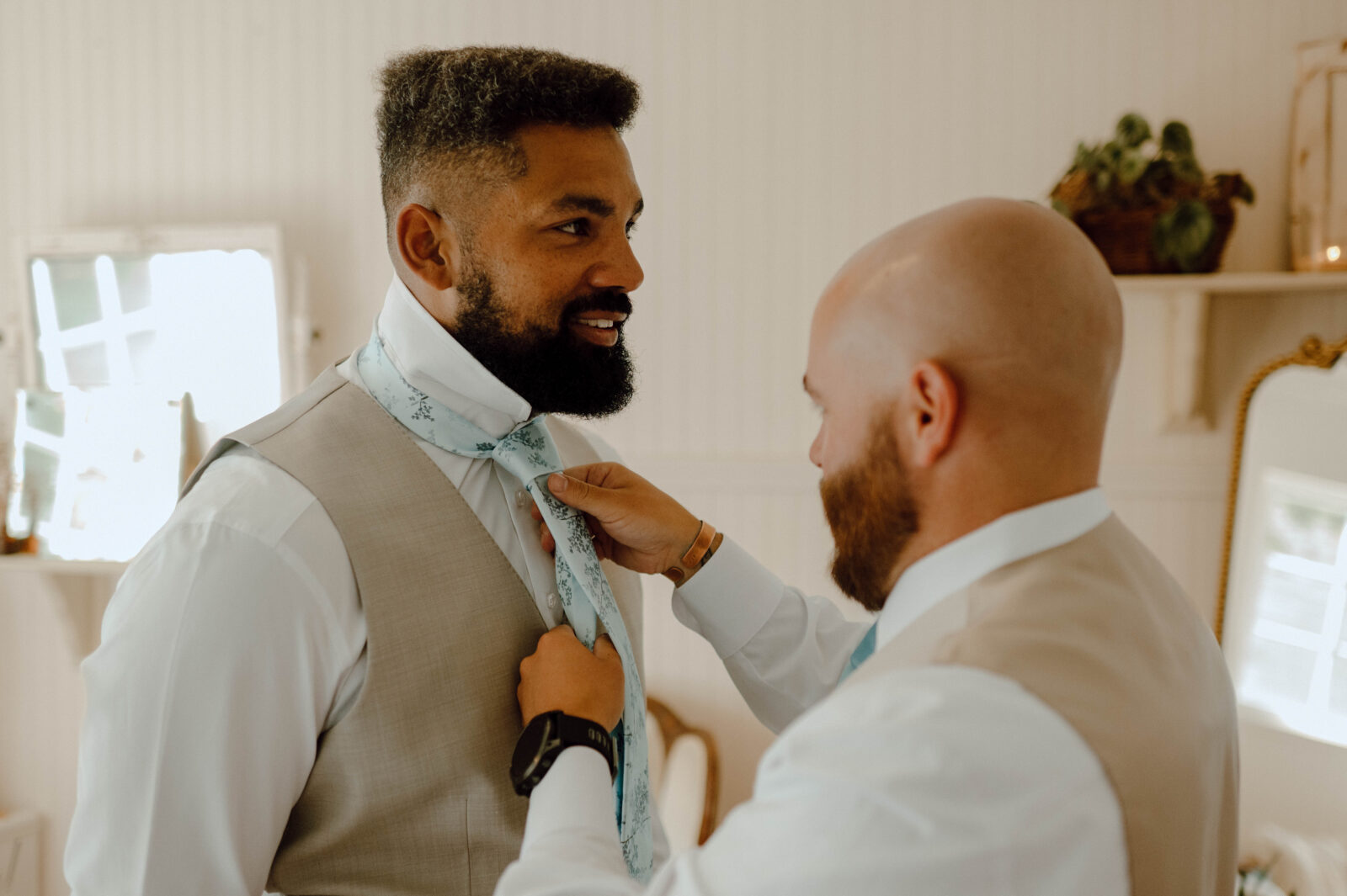 Groomsman helping the groom adjust his tie before his Gansberg Rnach wedding.