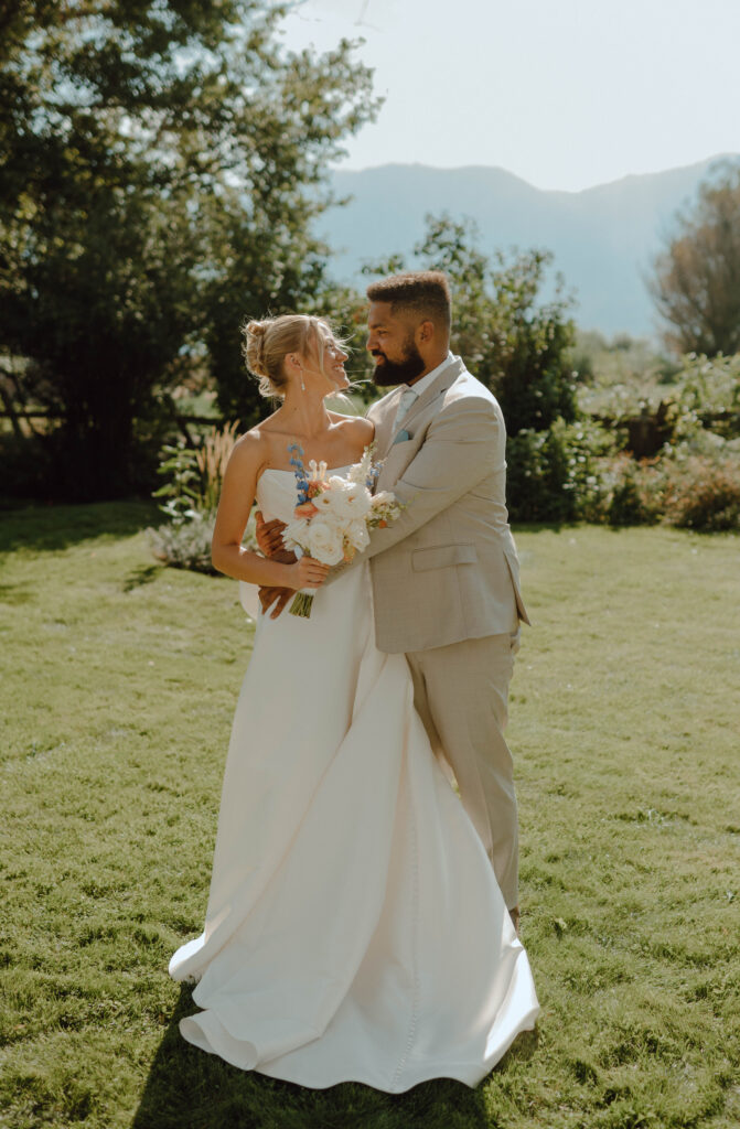Bride and groom standing together on the lawn with mountains in the background.