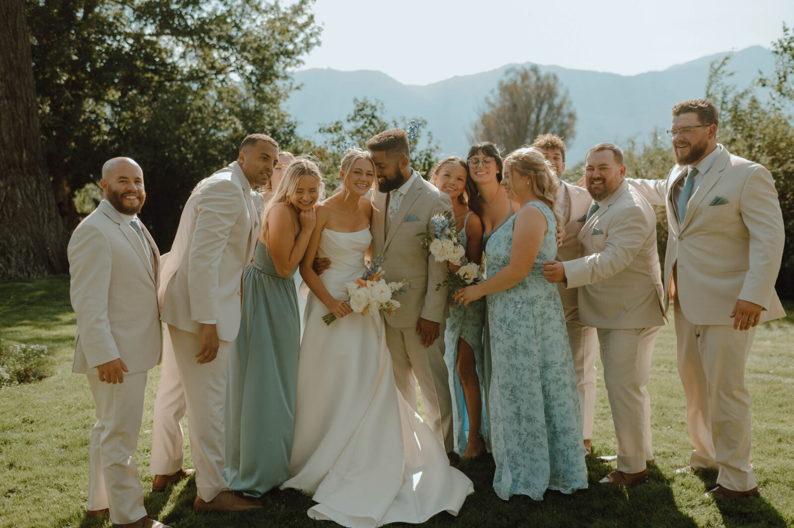 Bride and groom surrounded by their wedding party for a fun outdoor group portrait.