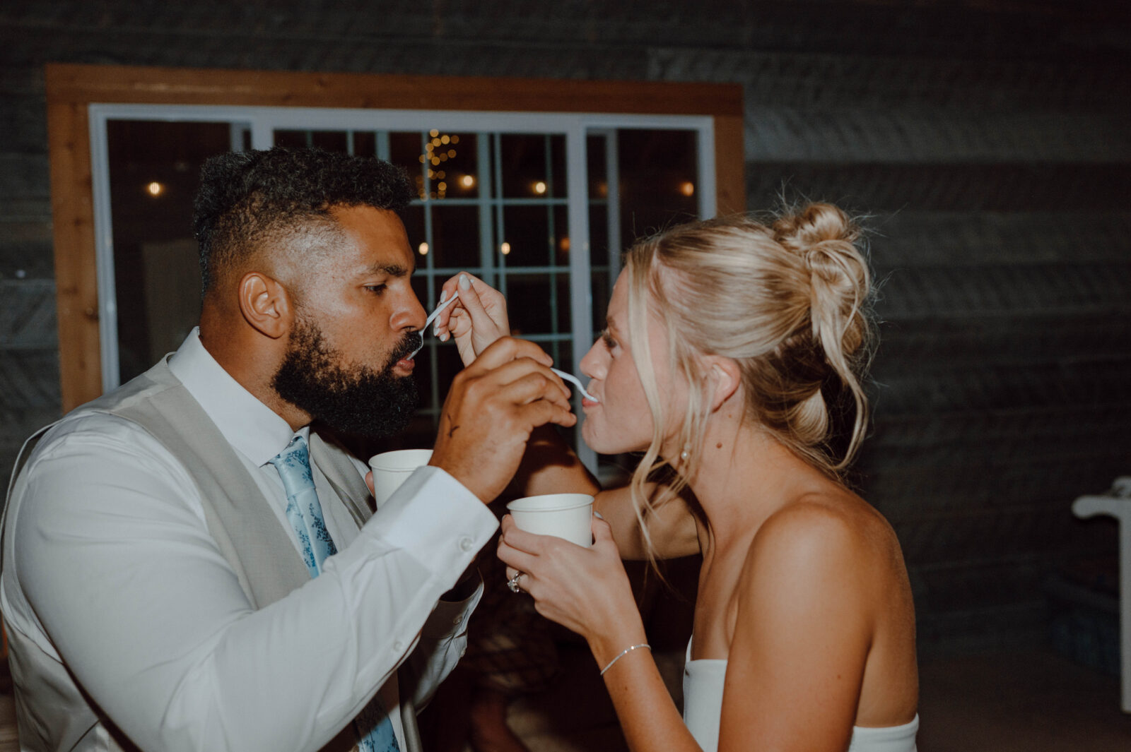 Bride and groom feeding each other ice cream during their reception.