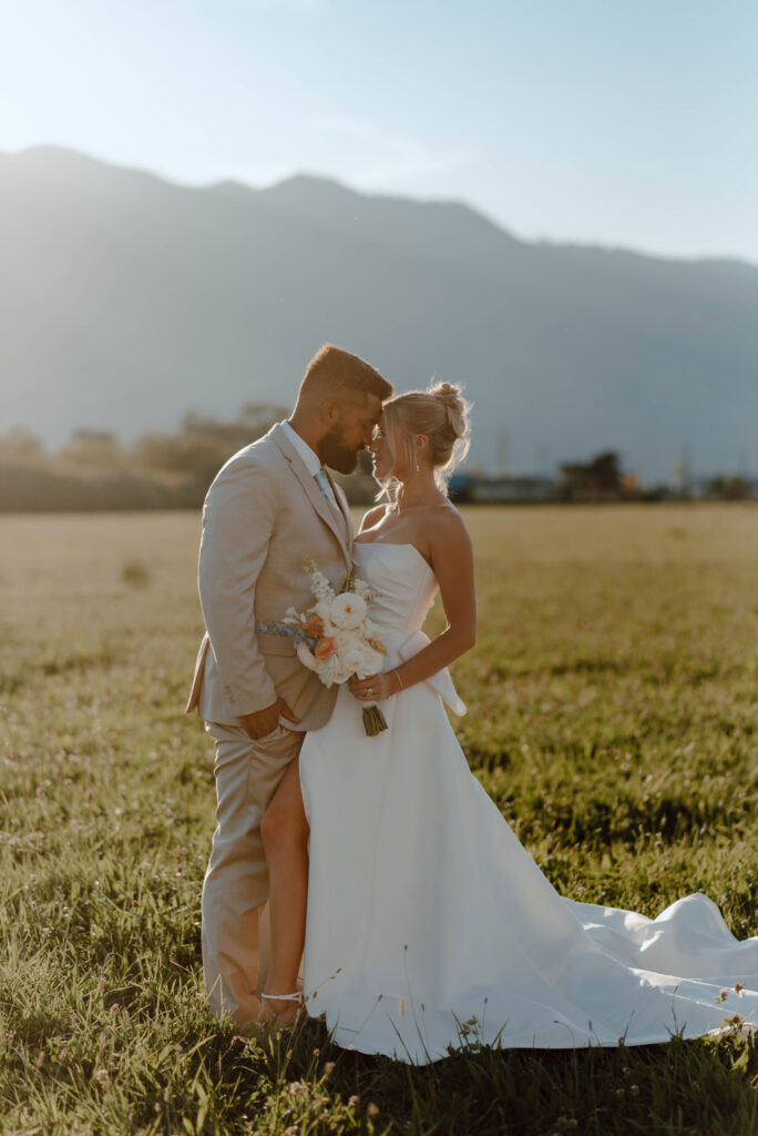 Bride and groom standing together in an open field with mountain views at Gansberg Ranch.