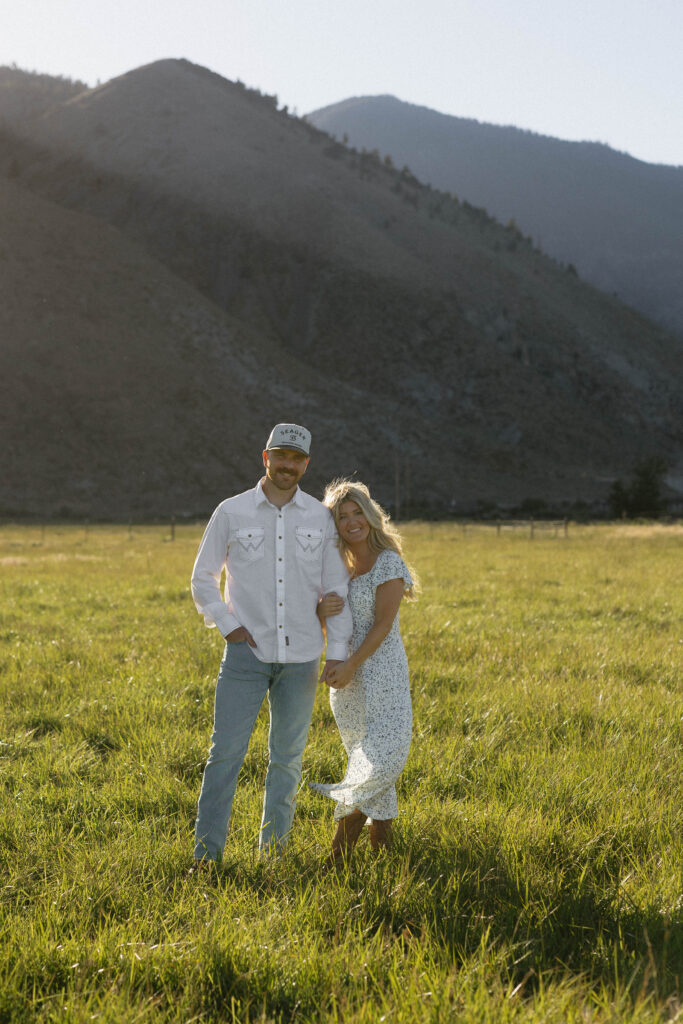 Couple posing with mountains behind them during golden hour.