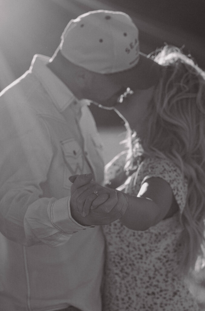 Couple holding their hands out towards the camera and kissing. 