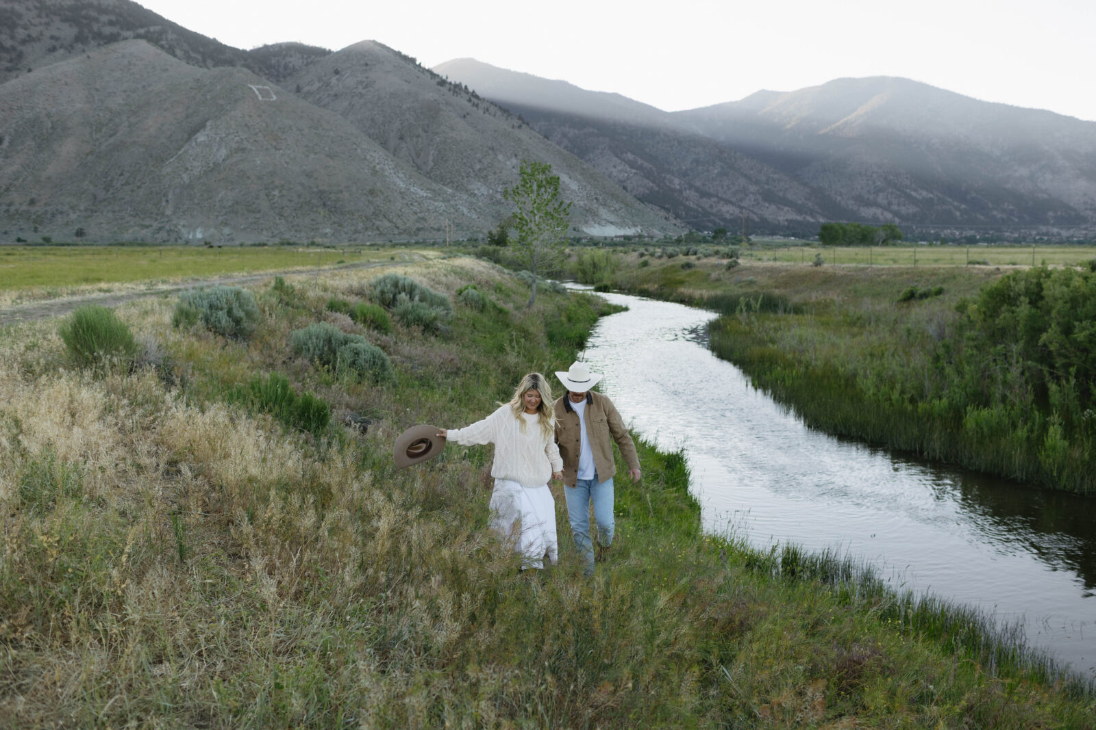 Couple walking by a river during their Jobs Peak engagement photos during blue hour. 
