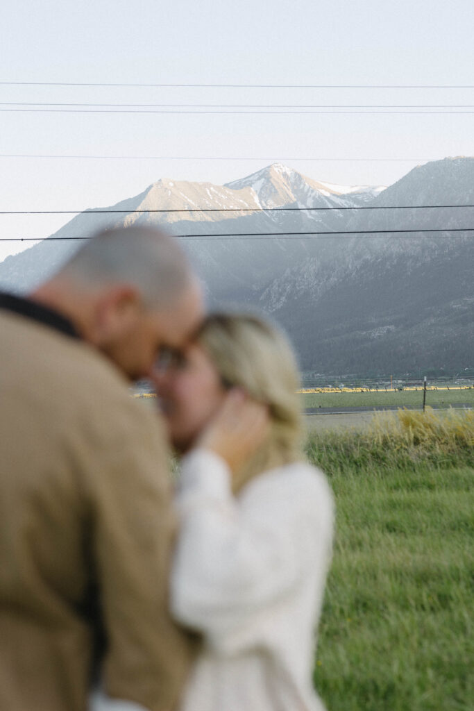 Couple touching noses during their blue hour hour engagement photos in Genoa, Nevada with Jobs Peak in the background.