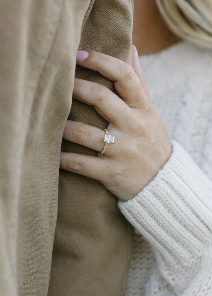 Woman holding her fiancés arm showing her engagement ring. 