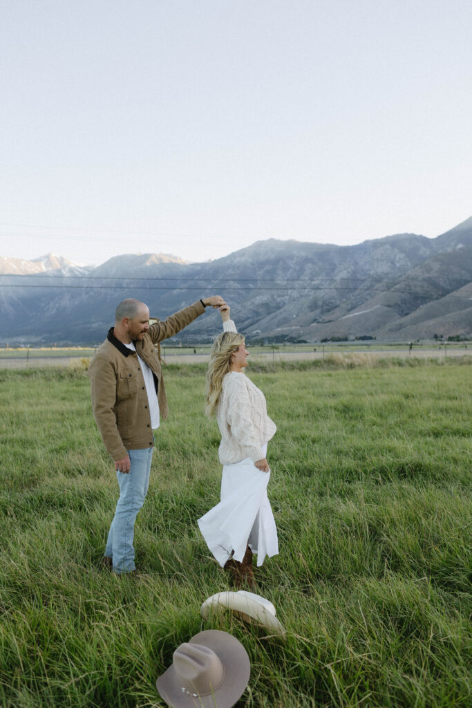 Man twirling his fiancé during their mountain engagement photos in Genoa Nevada with Jobs Peak in the background.
