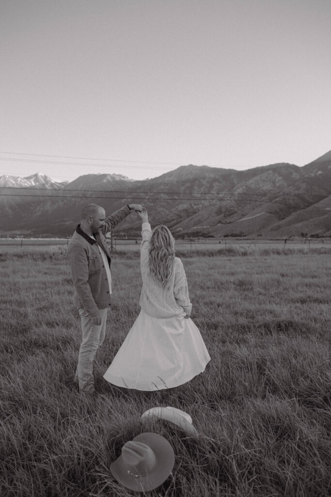 Man twirling his fiancé during their mountain engagement photos in Genoa Nevada with Jobs Peak in the background.