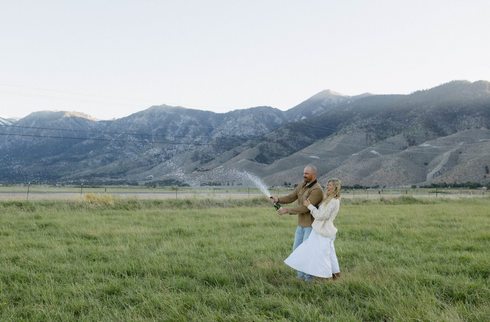 Couple popping champagne during their Genoa Nevada engagement photos at Jobs Peak during blue hour. 