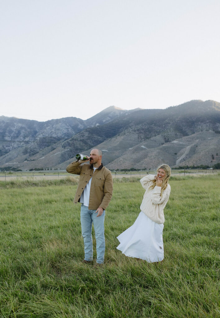 Couple drinking champagne during their blue hour Nevada engagement photos in Genoa with Jobs Peak in the background. 